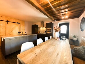 Una cocina moderna con encimera de madera, electrodomésticos integrados y una zona de comedor con mesa y sillas de madera.