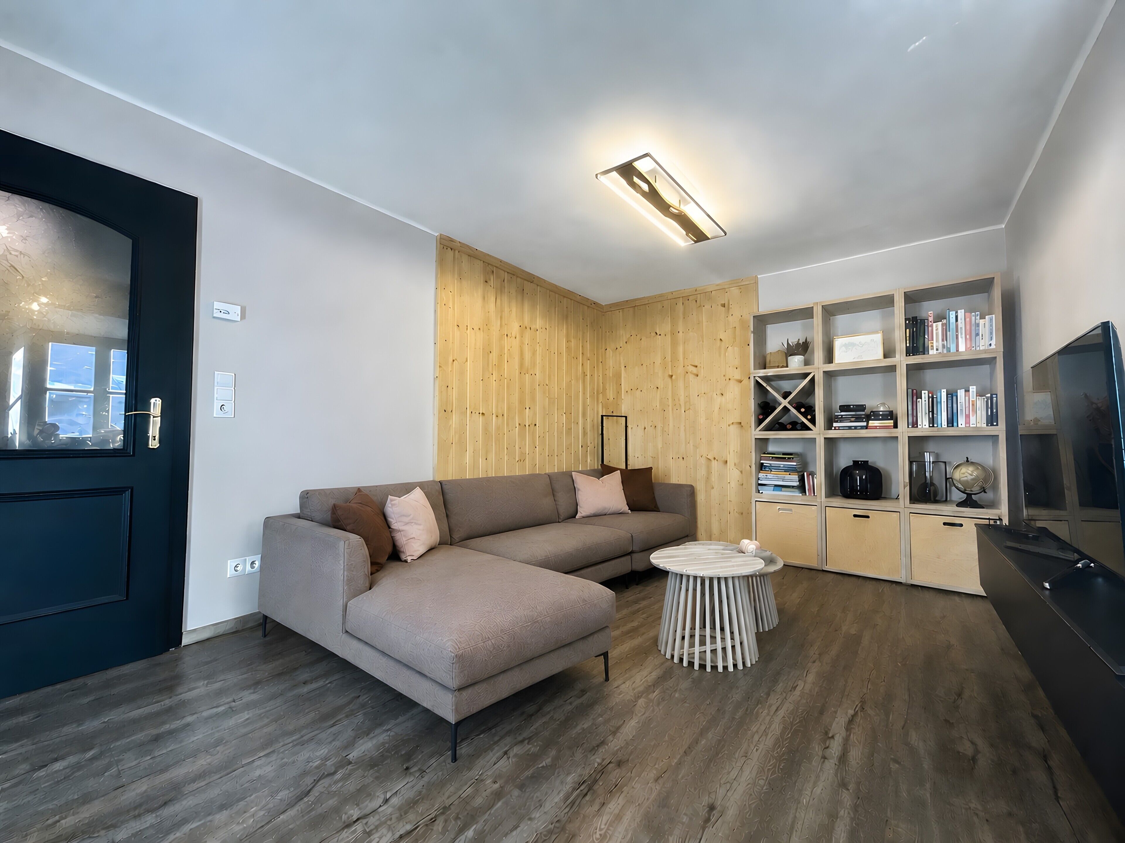 A modern living room with a sectional sofa, a small round table, and a built-in bookshelf.