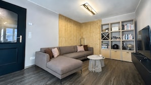 Una sala moderna con un sofá modular, una mesita redonda y una estantería empotrada.