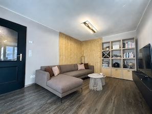 Una sala moderna con un sofá modular, una mesita redonda y una estantería empotrada.