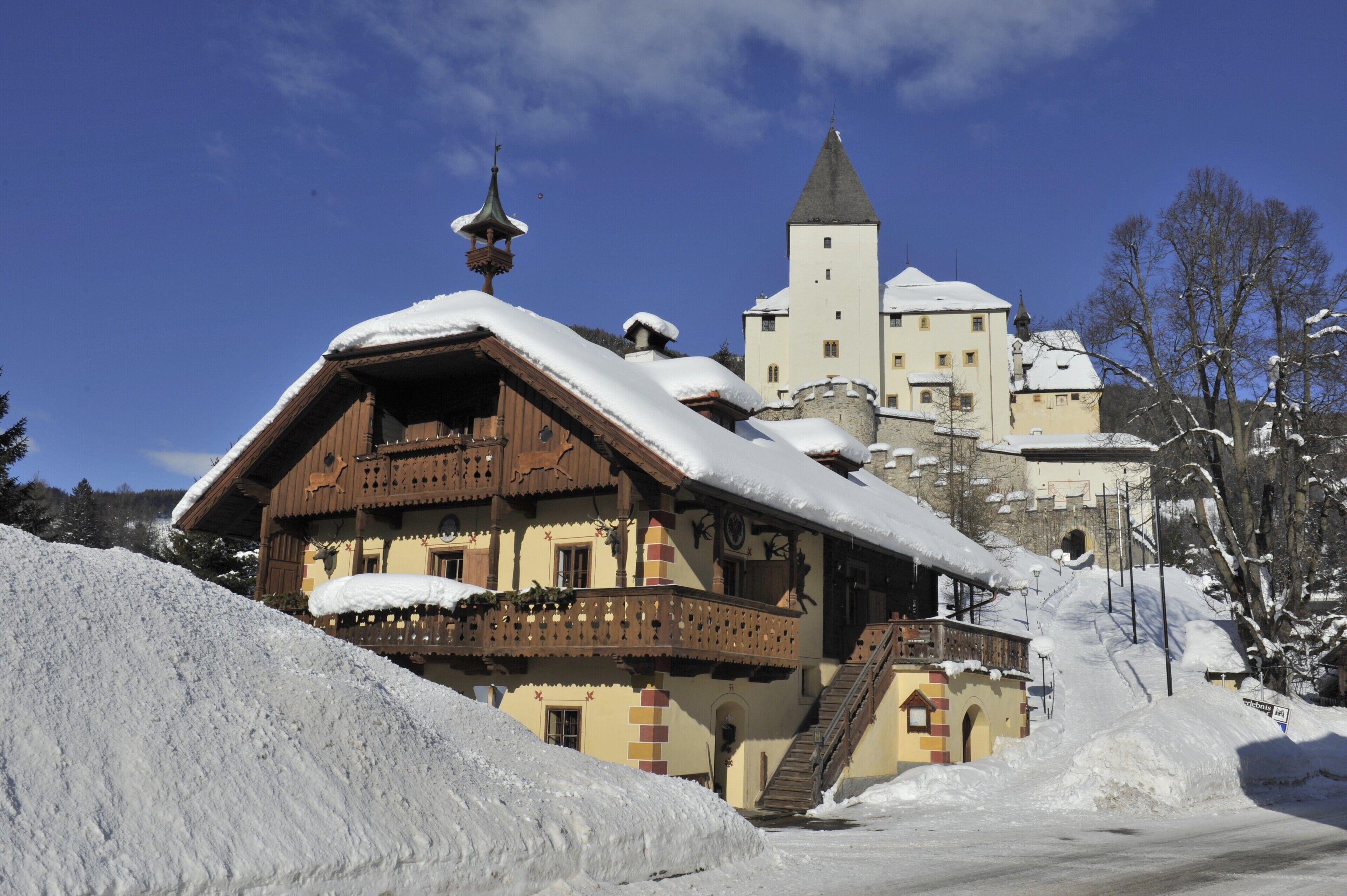 Un chalet traditionnel avec un toit à forte pente, des balcons en bois et une tour en arrière-plan.