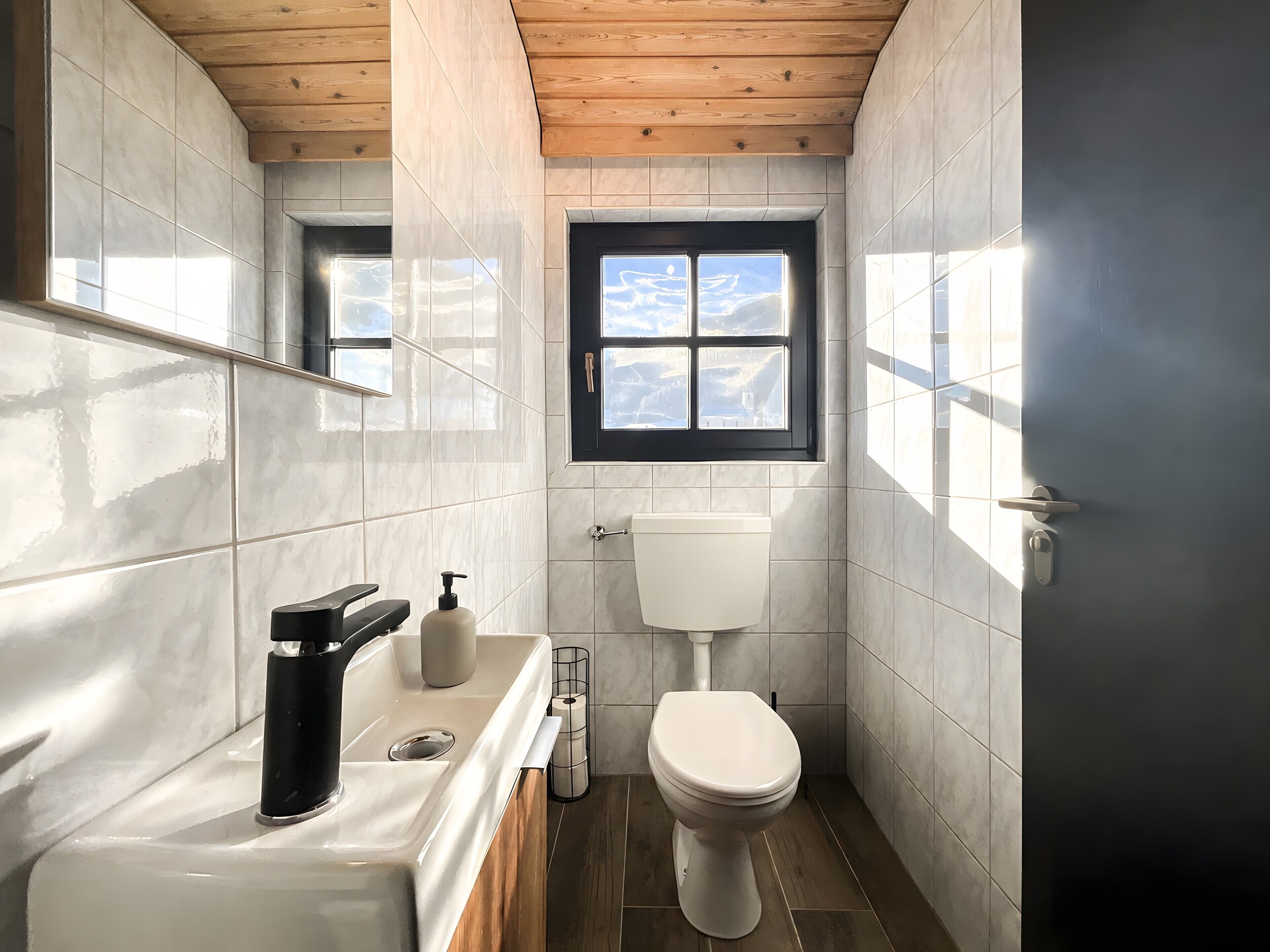 A small bathroom with a toilet, sink, and window.