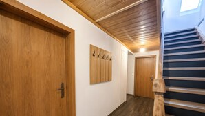 Un pasillo con puertas de madera, un perchero y una escalera.