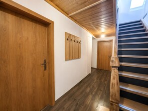 Un pasillo con puertas de madera, un perchero y una escalera.