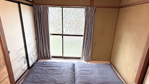 A room with a traditional Japanese-style interior, featuring tatami flooring, shoji screens, and a futon bed setup. - NEO-Japanese House with Sauna in Rice Fields | Pet-Friendly·Workspace·Kitchen (佐久市)