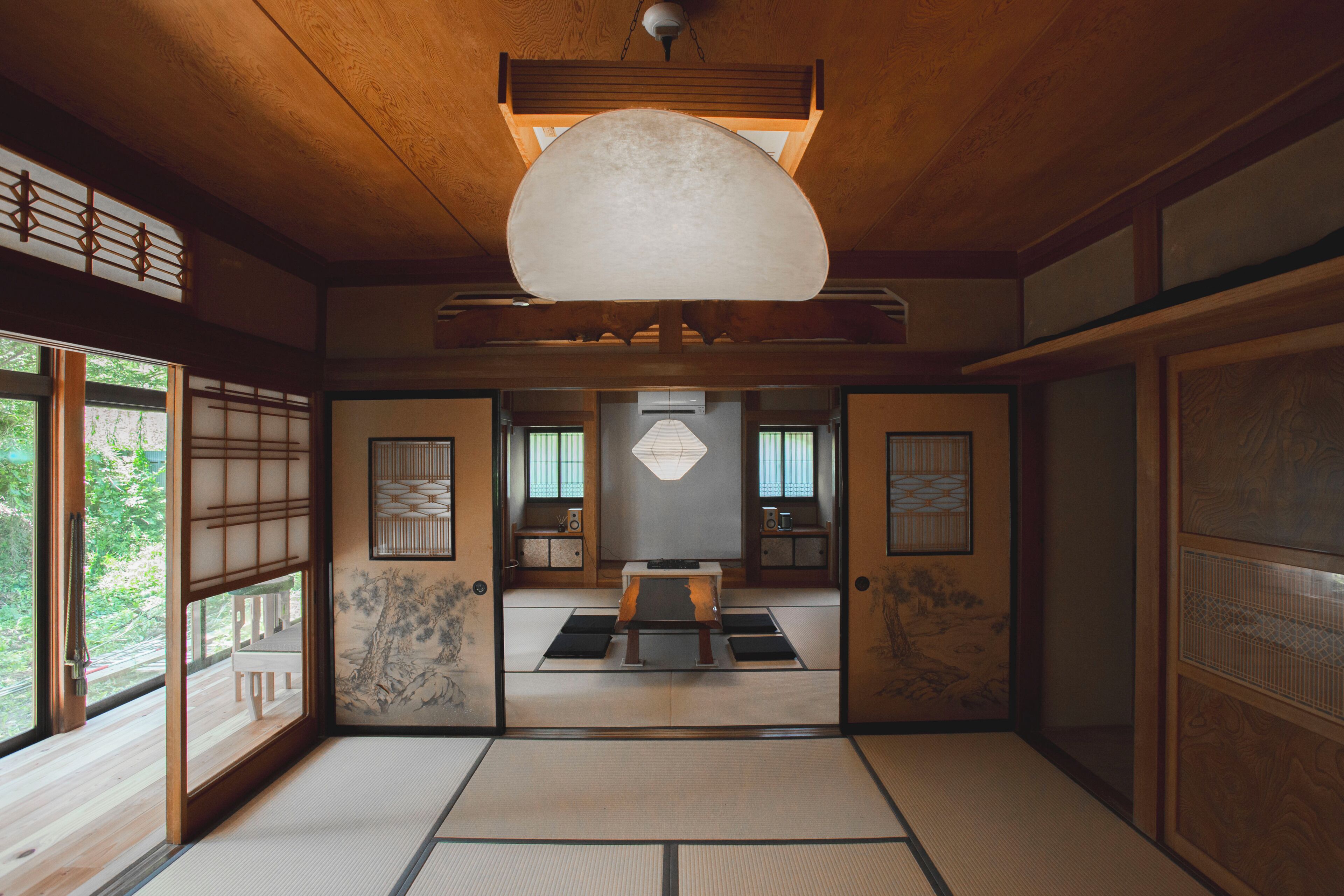 Una habitación japonesa tradicional con suelo de tatami, puertas correderas y una mesa baja de tatami en el centro.