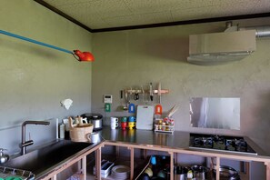 A kitchen with a stainless steel sink, a stove, and various utensils and appliances.