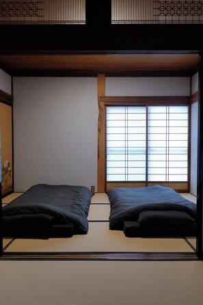 Une pièce de style japonais traditionnel, avec un sol recouvert de tatamis, une fenêtre à panneaux coulissants (shoji) et un plafond bas.
