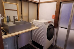 A compact bathroom with a sink, mirror, and a front-loading washing machine. - NEO-Japanese House with Sauna in Rice Fields | Pet-Friendly·Workspace·Kitchen (佐久市)
