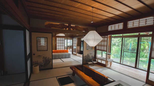 A traditional Japanese interior with tatami flooring, a low wooden table, and a view of greenery outside. - NEO-Japanese House with Sauna in Rice Fields | Pet-Friendly·Workspace·Kitchen (佐久市)