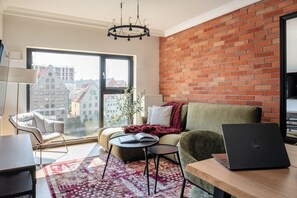 Ein modernes Wohnzimmer mit großem Fenster, einer Ziegelwand und einem Laptop auf einem Tisch.
