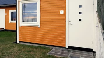 A single-story building with a white door and window, a small porch area, and a number '1' sign.