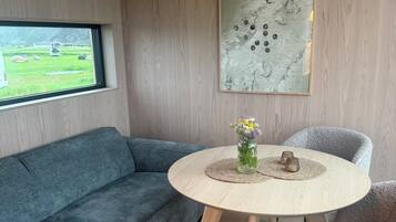 Un salón moderno con un sofá azul, una mesa redonda de madera con un florero y un mapa en la pared.