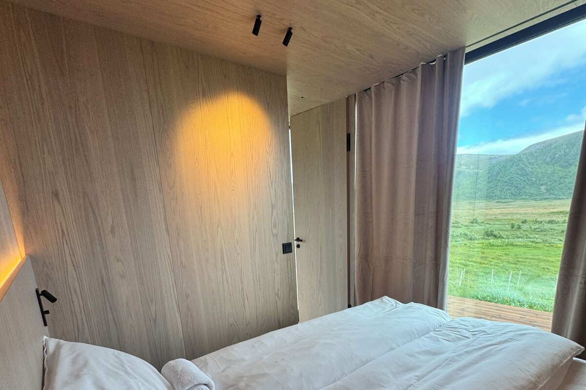 Un dormitorio con una cama grande, paredes de madera y una ventana con cortinas.
