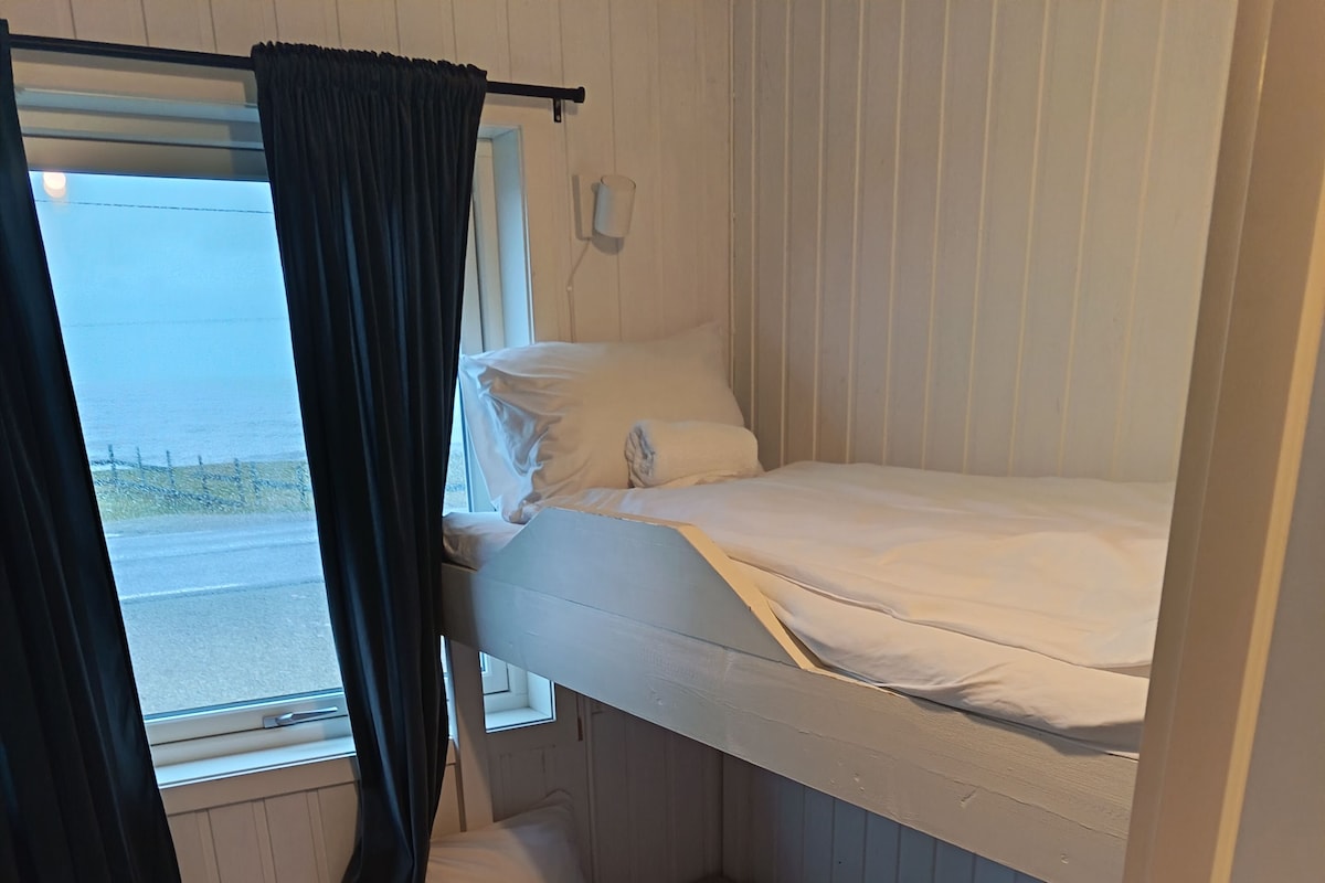 A bunk bed room with a window, a bedside lamp, and a power outlet.