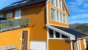 Uma casa de dois andares com telhado inclinado, varanda frontal e garagem.