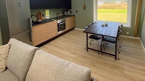 Uma cozinha moderna com claraboias, área de jantar com mesa e cadeiras, e um sofá.