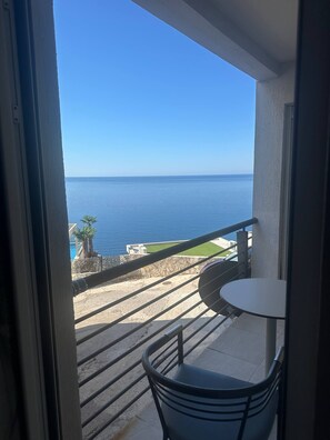 Un balcón con vista al mar, una mesa pequeña y una silla.