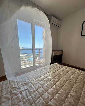 Una camera da letto con un letto grande, una finestra vista mare e un comodino.