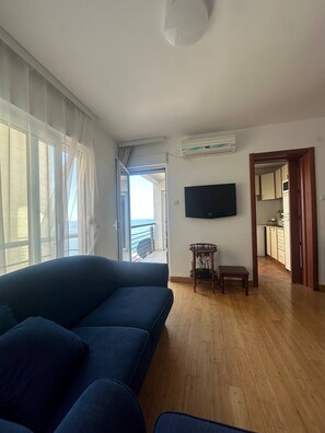 Un soggiorno con un divano, una TV a parete e vista sull'esterno.