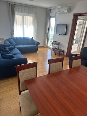 A living room with a sofa, a dining table, and chairs. - Aurora Top location views of Old Budva and Adriatic (Budva)