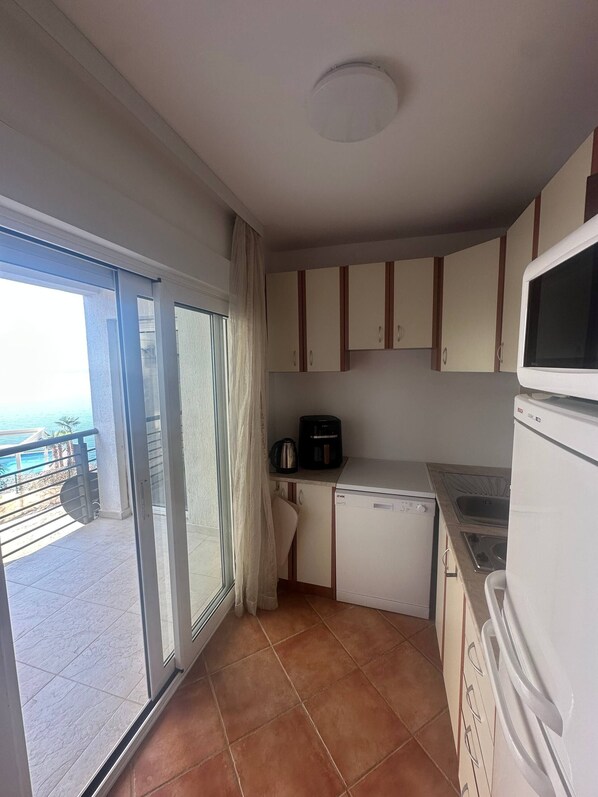 Una cucina compatta con forno a microonde integrato, macchina del caffè e lavastoviglie.