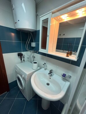 Un bagno dotato di lavatrice, lavabo, specchio e porta asciugamani.