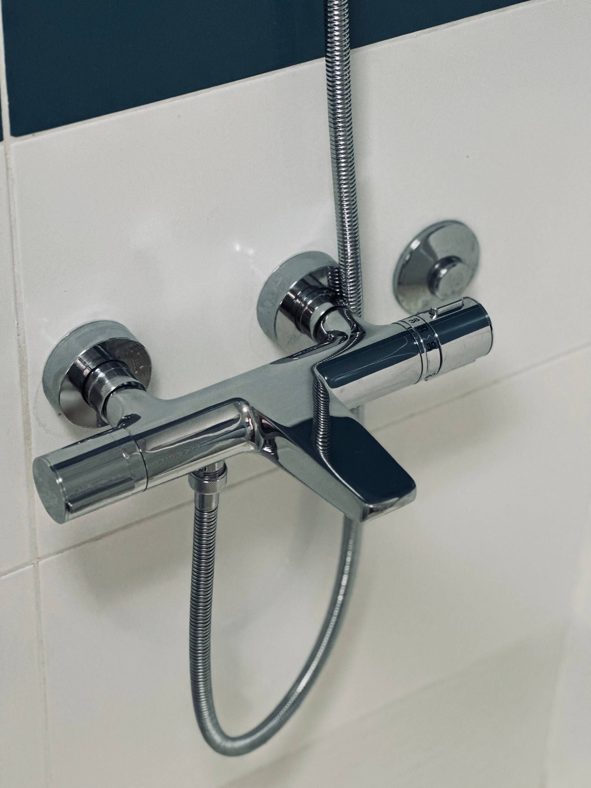 A chrome shower control with multiple handles and a flexible hose.