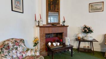 A traditional room with a fireplace, floral armchair, and a table with candles.