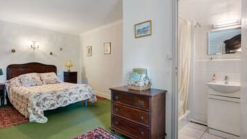 Een slaapkamer met een bed, een dressoir en een badkamer met een wastafel en spiegel.