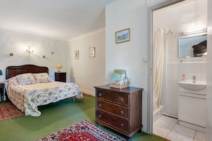A bedroom with a bed, dresser, and a bathroom with a sink and mirror.