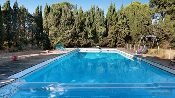 Ein rechteckiger Pool mit Fliesenrand, umgeben von einer Holzdielen-Terrasse.