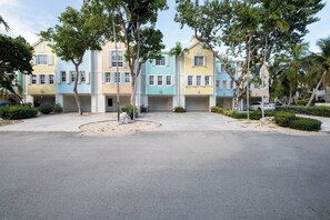 Une rangée de maisons de ville aux façades colorées, avec une allée pavée et des aménagements paysagers.