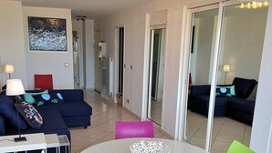 A modern living room with a round table, colorful chairs, a sofa, and a large mirror. - Première ligne, t2 cabine pour 4 N123 (Palavas-les-Flots)