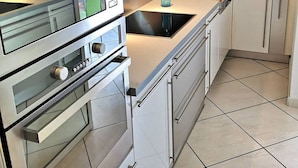A modern kitchen with stainless steel appliances, a built-in oven, and a sink. - Première ligne, t2 cabine pour 4 N123 (Palavas-les-Flots)