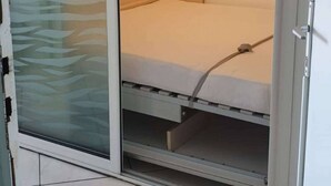 A room with a bed, a sliding door, and a wall with abstract art. - Première ligne, t2 cabine pour 4 N123 (Palavas-les-Flots)