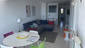 A modern living room with a sofa, a dining table with chairs, and artwork on the walls. - Première ligne, t2 cabine pour 4 N123 (Palavas-les-Flots)