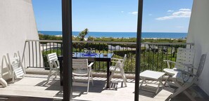 Un balcon avec une table et des chaises, donnant sur une plage.