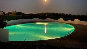 Une piscine au crépuscule, sous un ciel dégagé et avec une lune bien visible.
