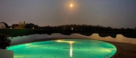 Una piscina al anochecer con cielo despejado y una luna visible.