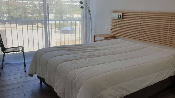 Une chambre à coucher comprenant un lit, une chaise, une table de chevet et une tête de lit en bois.