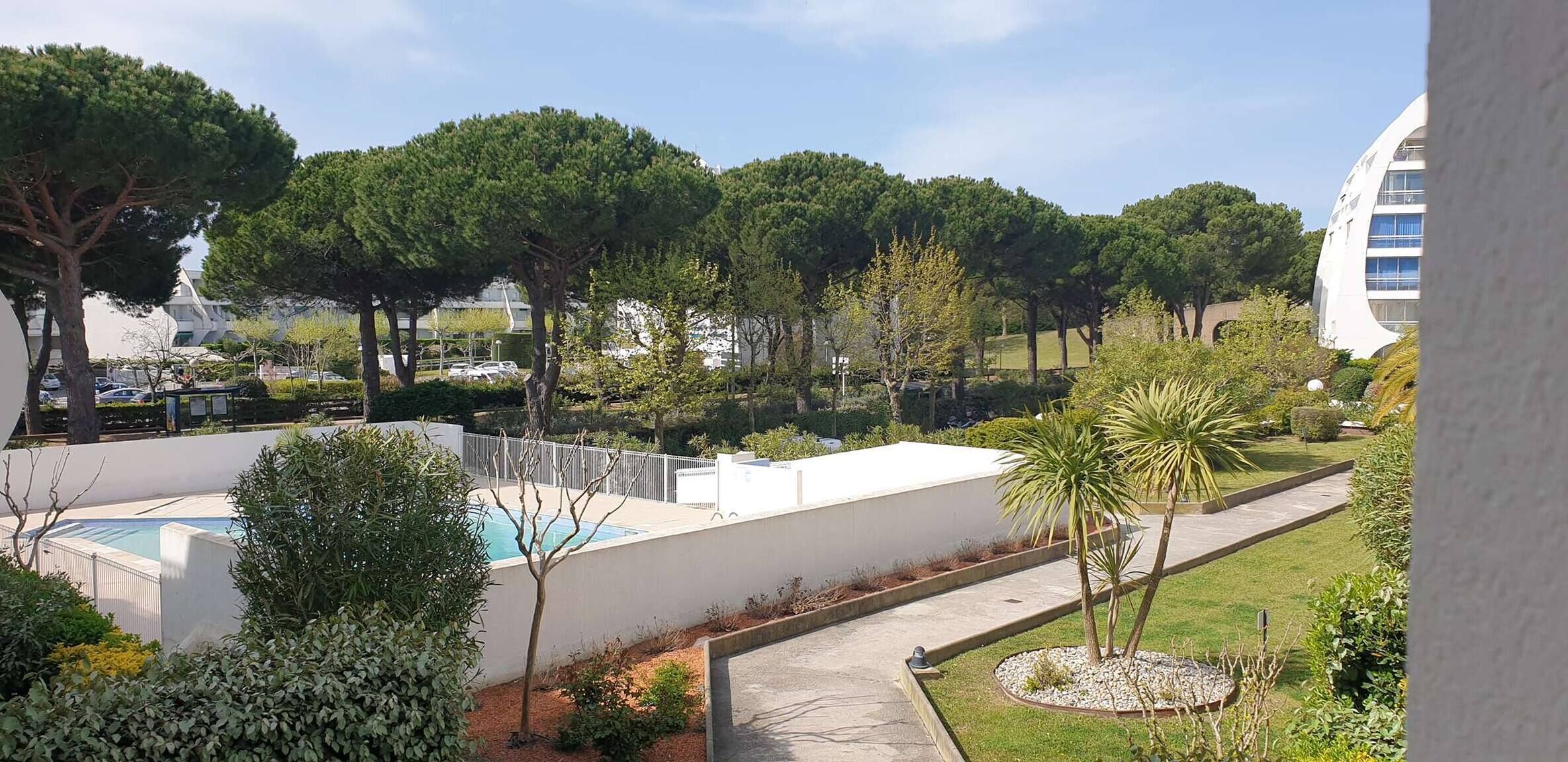 Un espace piscine offrant une vue dégagée sur la végétation environnante et un bâtiment moderne en arrière-plan.