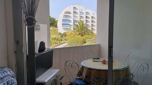 Un balcone con vista su un edificio moderno, un tavolino con una sedia e una pianta in vaso.