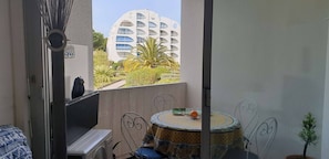 Ein Balkon mit Blick auf ein modernes Gebäude, ein kleiner Tisch mit einem Stuhl und ein Blumentopf.