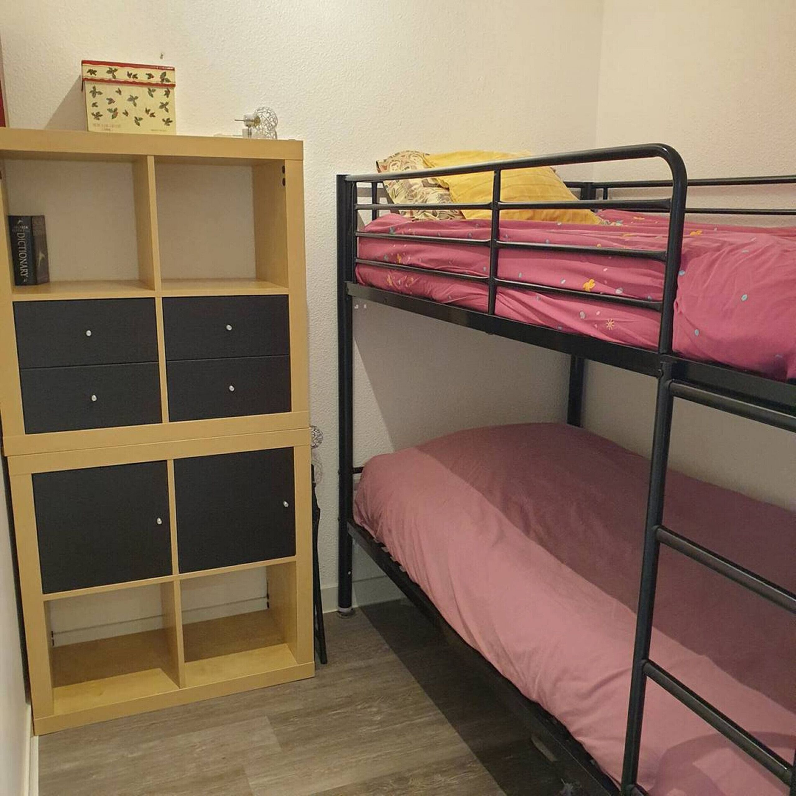 Un lit superposé avec un meuble de rangement en bois à côté.