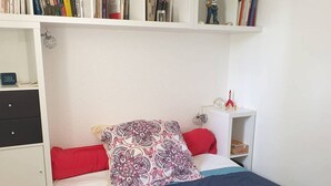 Una camera da letto con un letto, un comodino, una libreria e un comò.