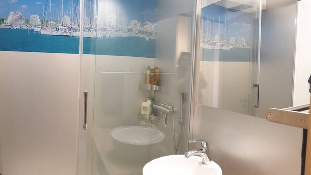 Un bagno moderno con doccia vetrata, lavandino bianco e specchio.