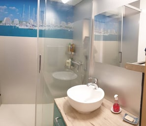 A modern bathroom with a glass-enclosed shower, a white sink, and a mirror.