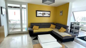 Een moderne woonkamer met een hoekbank, een salontafel en een vloerkleed met een geometrisch patroon.