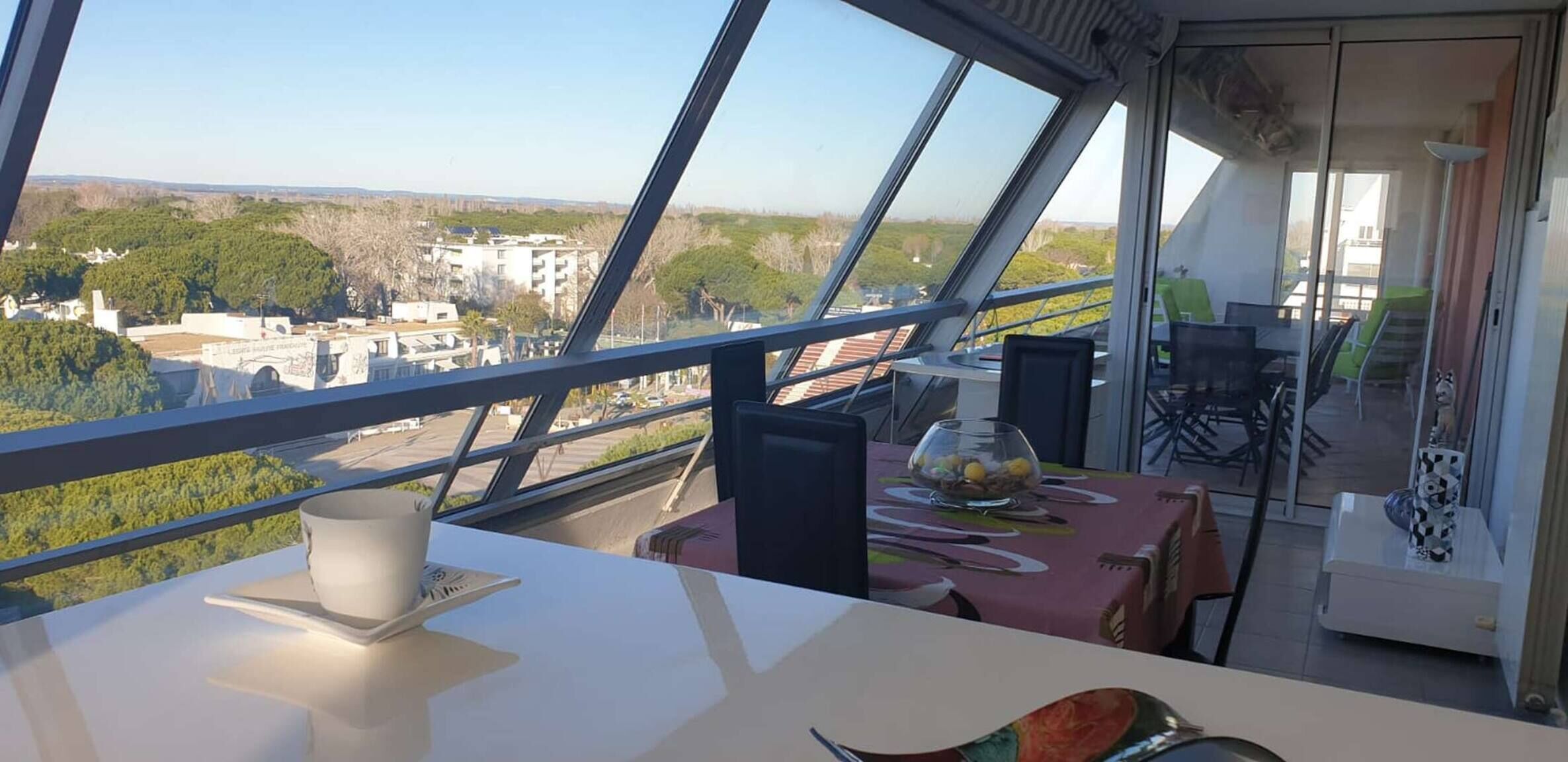 Un comedor con una mesa, sillas y vistas de la ciudad a través de amplias ventanas.